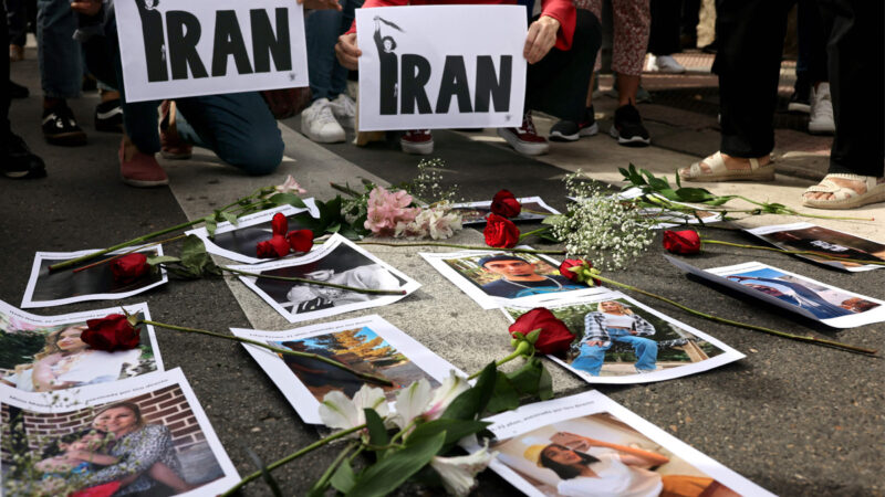 2022年9月28日，在伊朗駐馬德里大使館前，西班牙抗議者在伊朗受害者照片旁邊舉著標語。（THOMAS COEX/AFP via Getty Images）