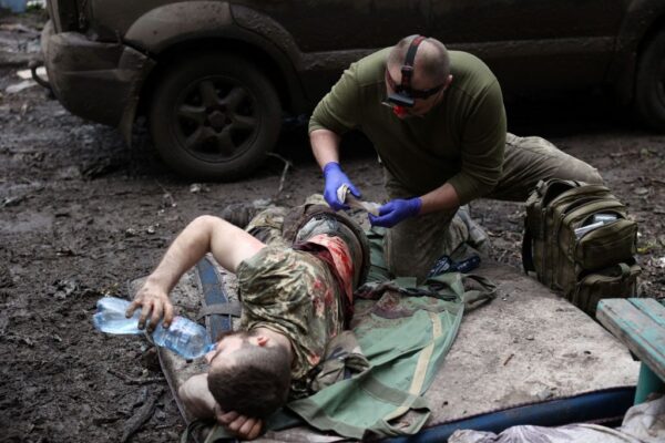 2023年4月23日，在俄羅斯入侵烏克蘭的情況下，一名軍事救護人員在頓涅茨克州前線城市巴赫穆特的一條街道上治療一名烏克蘭受傷軍人。（ANATOLII STEPANOV/AFP via Getty Images）