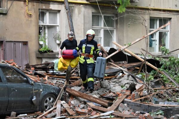 2023年7月3日,烏克蘭東部城市蘇米,無人機襲擊造成2人死亡、19人受傷,一名救援人員幫助一名當地居民將其物品從一棟五層高的住宅樓中搬出。(SERGEY BOBOK/AFP via Getty Images)