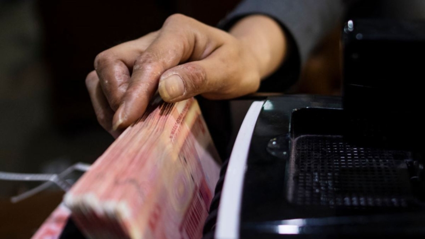 一名職員正在使用點鈔機清點人民幣現鈔。示意圖與新聞無關。 （JOHANNES EISELE/AFP via Getty Images）