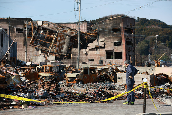 2024 年 1 月 31 日,石川縣能登地區發生 7.5 級大地震近一個月後,在石川縣輪島市被大火燒燬的旅遊景點 Asaichi Dori 周圍,人們看到一名男子站立。(STR/JIJI Press/AFP via Getty Images)