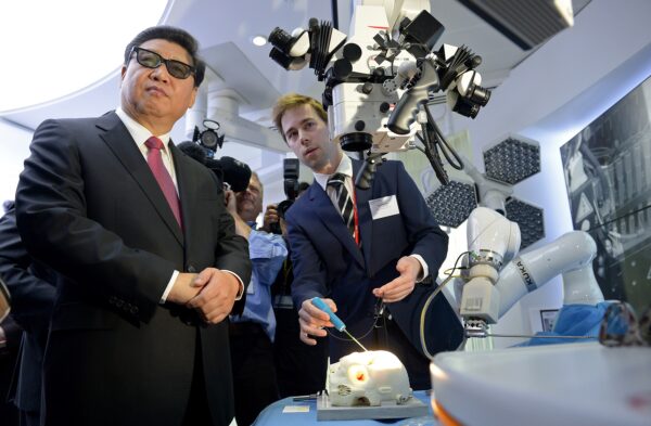 2015年10月21日，中共領導人習近平（左）參觀倫敦帝國理工學院，在該校的哈姆林研究中心，習近平戴著3D眼鏡觀摩機械人微創手術展示。（Anthony Devlin/AFP via Getty Images）
